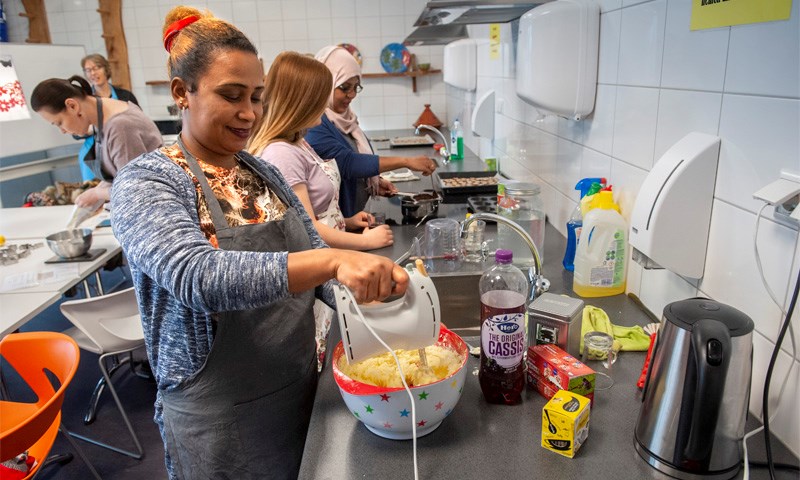 Deelnemers Taallessen Copernikkel bakken kerstkoekjes in de keuken van de BBS